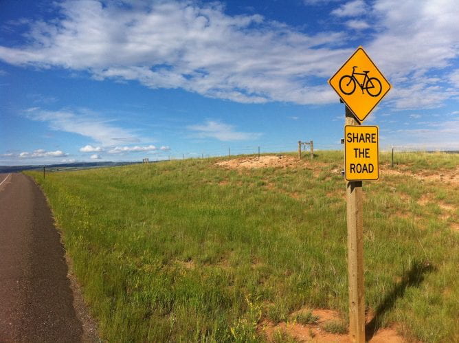Photo of road with a sign that shows a bicycle and says "share the road."